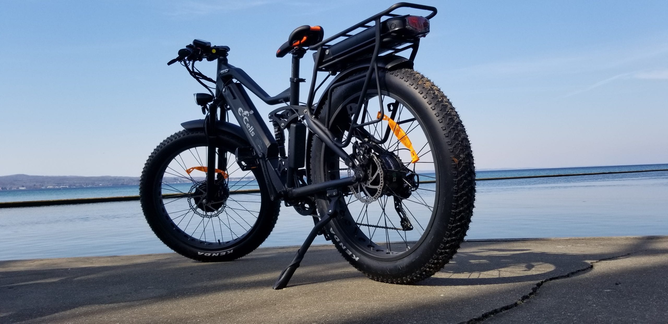 photo of a black E-Cells electric bike on a concrete walk by a shore